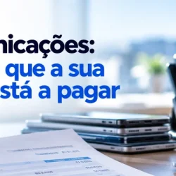 Faturas com os custos de telecomunicações da empresa numa secretária, com telemóveis, telefone fixo e portátil