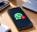 O WhatsApp bloqueia telemóveis desatualizados: aviso de alerta no ecrã de um telemóvel sobre uma secretária de escritório